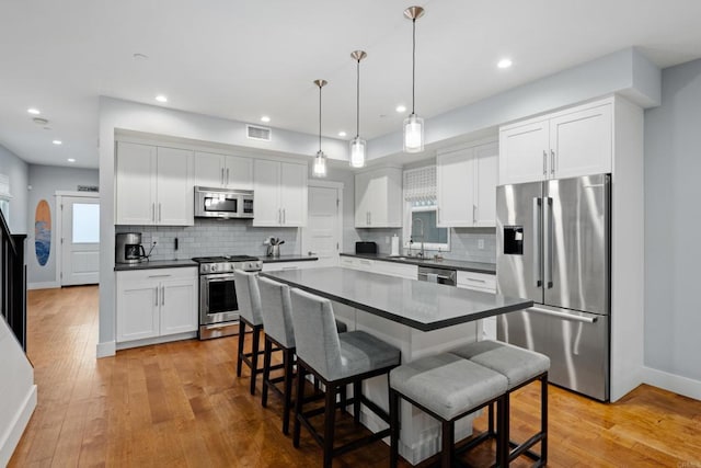 867 Wilbur Ave, San Diego, CA 92109 - kitchen with stainless steel appliances, dark countertops, a kitchen bar, decorative backsplash, and recessed lighting