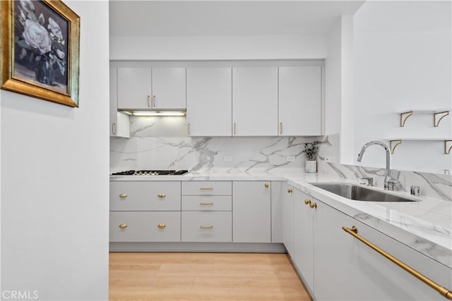 900 W Olympic Blvd Unit 34F, Los Angeles, CA 90015 - kitchen featuring a sink, gas stovetop, backsplash, under cabinet range hood, and light stone countertops