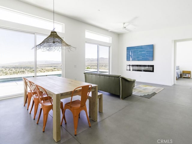 6197 Mandarin Rd, Yucca Valley, CA 92284 - dining area featuring ceiling fan, concrete flooring, and a glass covered fireplace