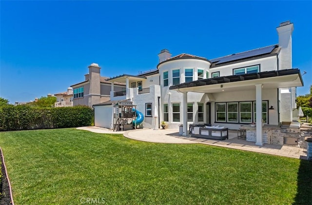 31 Harcourt, Newport Coast, CA 92657 - rear view of property featuring a chimney, exterior kitchen, a yard, roof mounted solar panels, and a patio area