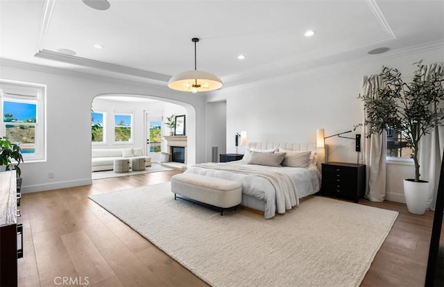 31 Harcourt, Newport Coast, CA 92657 - bedroom with a tray ceiling, arched walkways, wood finished floors, crown molding, and a glass covered fireplace