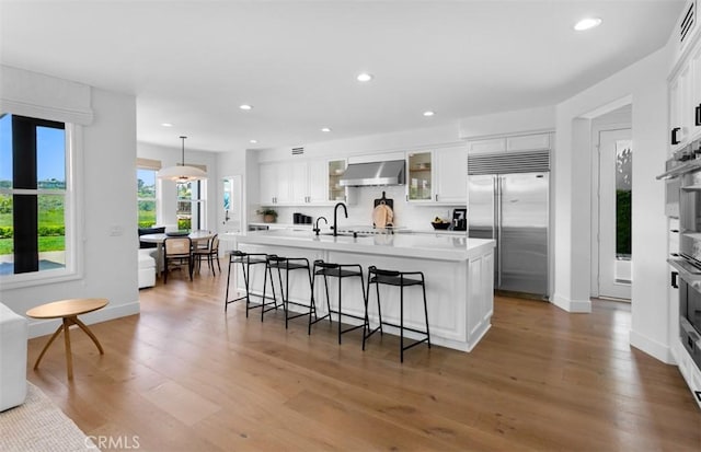 31 Harcourt, Newport Coast, CA 92657 - kitchen with stainless steel built in refrigerator, wall chimney exhaust hood, a kitchen breakfast bar, recessed lighting, and white cabinetry