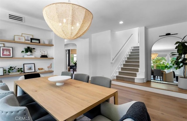 31 Harcourt, Newport Coast, CA 92657 - dining space featuring arched walkways, a chandelier, stairs, wood finished floors, and recessed lighting