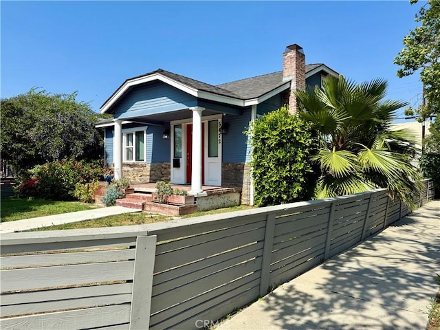 5472 3rd Ave, Los Angeles, CA 90043 - view of front of property with a fenced front yard, a chimney, stone siding, and a porch
