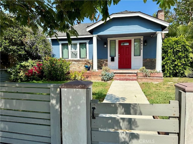 5472 3rd Ave, Los Angeles, CA 90043 - view of front facade featuring a chimney, a fenced front yard, stone siding, covered porch, and a gate
