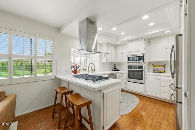 18751 Hatteras St Unit 13, Tarzana, CA 91356 - kitchen with stainless steel appliances, island range hood, a peninsula, recessed lighting, and light wood-style floors