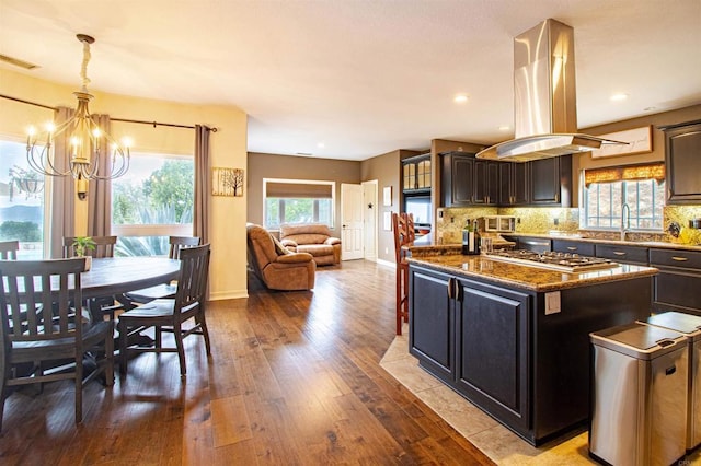 11606 Mesa Verde Dr, Valley Center, CA 92082 - kitchen with island range hood, a chandelier, stainless steel gas cooktop, hardwood / wood-style flooring, and decorative backsplash