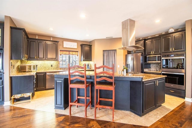 11606 Mesa Verde Dr, Valley Center, CA 92082 - kitchen featuring stainless steel appliances, island exhaust hood, an island with sink, tasteful backsplash, and light stone countertops