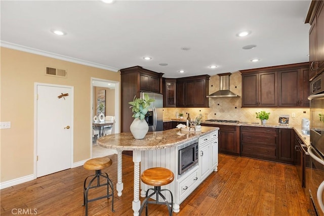 29162 Bobolink Dr, Laguna Niguel, CA 92677 - kitchen featuring stainless steel appliances, wall chimney range hood, a kitchen bar, light stone counters, and wood-type flooring