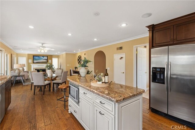 29162 Bobolink Dr, Laguna Niguel, CA 92677 - kitchen with appliances with stainless steel finishes, a ceiling fan, arched walkways, crown molding, and a warm lit fireplace
