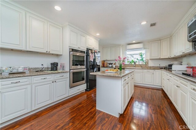 1855 Turnbull Canyon Rd, Hacienda Heights, CA 91745 - kitchen with double oven, freestanding refrigerator, a wall unit AC, dark wood-type flooring, and white cabinetry