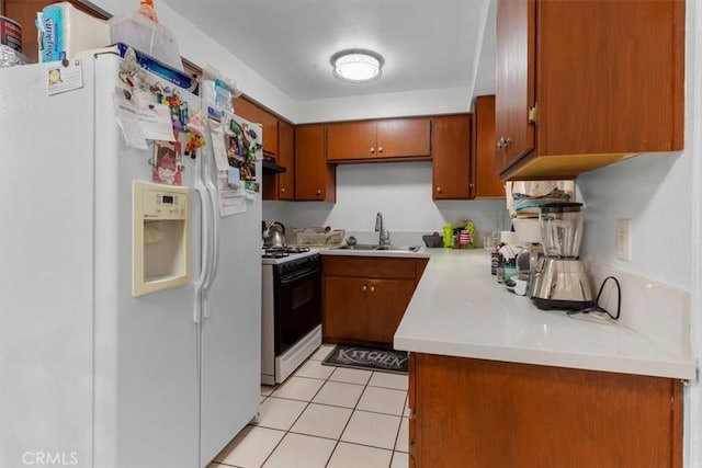 12912 Lariat Ln, Norwalk, CA 90650 - kitchen featuring white refrigerator with ice dispenser, gas range, a sink, brown cabinets, and light countertops