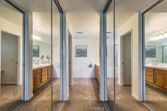 32091 Camino Nunez, Temecula, CA 92592 - bathroom with two vanities, a bath, a textured ceiling, and tile patterned flooring