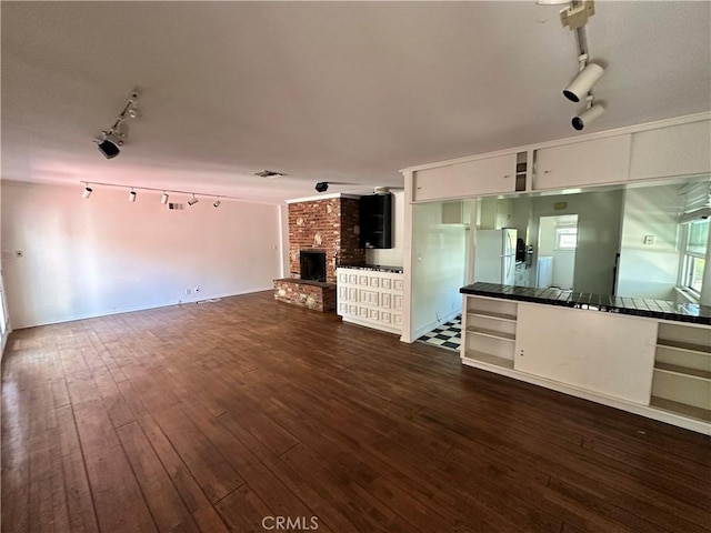14655 Morrison St, Sherman Oaks, CA 91403 - unfurnished living room featuring rail lighting, a brick fireplace, and dark wood finished floors