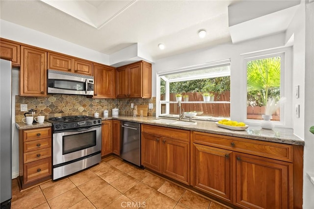 925 Calle Hermosa, San Dimas, CA 91773 - kitchen featuring appliances with stainless steel finishes, brown cabinetry, backsplash, light stone counters, and plenty of natural light
