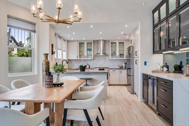 3285 5th Ave, San Diego, CA 92103 - kitchen featuring wall chimney exhaust hood, white stove, freestanding refrigerator, a chandelier, and decorative backsplash