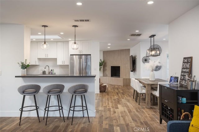 1792 Kenwood Pl, Costa Mesa, CA 92627 - kitchen featuring freestanding refrigerator, dark countertops, white cabinetry, a breakfast bar area, and dark wood-type flooring