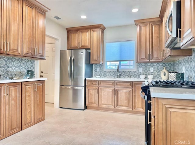 610 N Northwood Ave, Compton, CA 90220 - kitchen with stainless steel appliances, light countertops, backsplash, brown cabinets, and recessed lighting