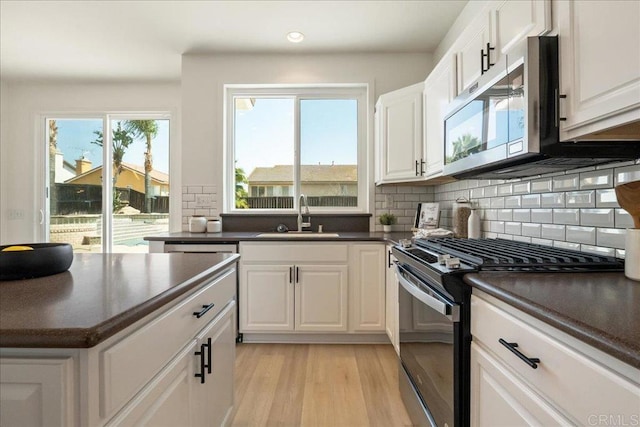 29589 Hazel Glen Rd, Murrieta, CA 92563 - kitchen with stainless steel appliances, dark countertops, backsplash, light wood-style flooring, and white cabinetry