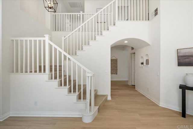 29589 Hazel Glen Rd, Murrieta, CA 92563 - stairs featuring arched walkways, a towering ceiling, wood finished floors, and a chandelier