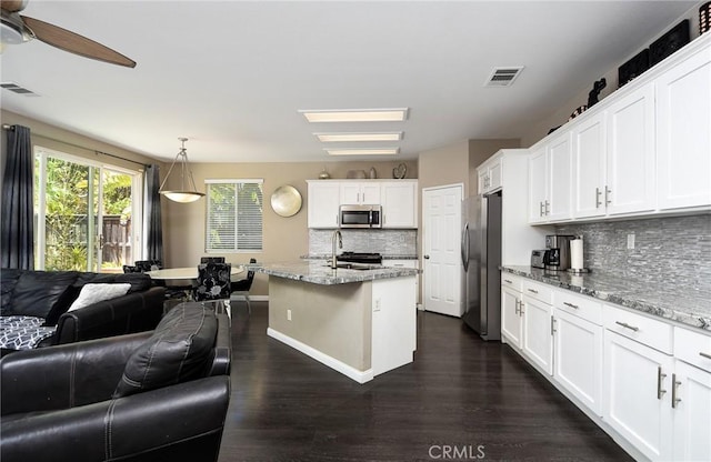 38919 Hickory Hill Ct, Murrieta, CA 92563 - kitchen with stainless steel appliances, open floor plan, backsplash, dark wood-style floors, and light stone counters