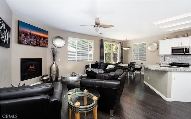 38919 Hickory Hill Ct, Murrieta, CA 92563 - living room featuring dark wood-style flooring, a ceiling fan, and a warm lit fireplace