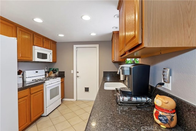 9614 Peach Ave, Hesperia, CA 92345 - kitchen with white appliances, recessed lighting, brown cabinets, light tile patterned flooring, and dark stone counters