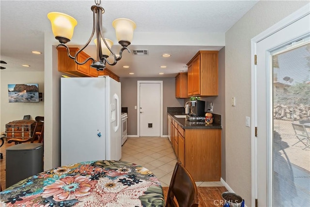 9614 Peach Ave, Hesperia, CA 92345 - kitchen featuring white appliances, dark countertops, a chandelier, brown cabinets, and light tile patterned flooring