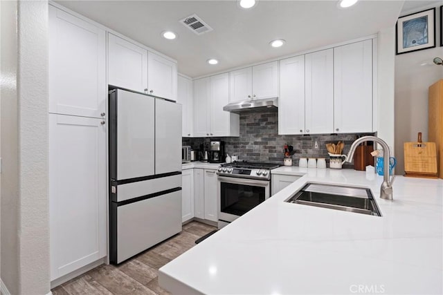 2141 Triador St Unit 103, Corona, CA 92879 - kitchen with freestanding refrigerator, stainless steel range with gas stovetop, a sink, under cabinet range hood, and light wood-style floors