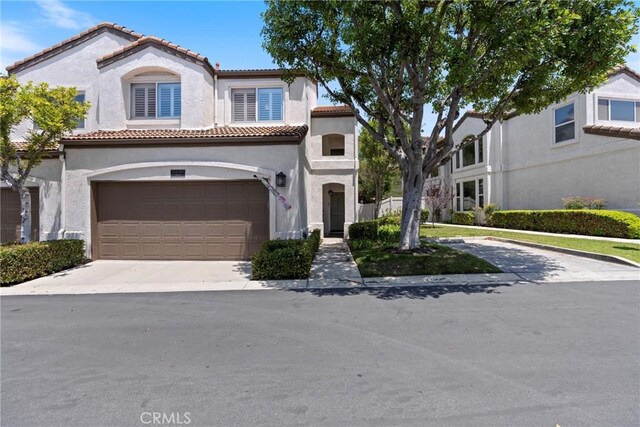 2141 Triador St Unit 103, Corona, CA 92879 - mediterranean / spanish home featuring a tiled roof, stucco siding, an attached garage, and concrete driveway