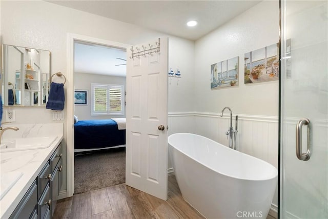 2141 Triador St Unit 103, Corona, CA 92879 - ensuite bathroom featuring wood finished floors, double vanity, a soaking tub, a wainscoted wall, and a stall shower