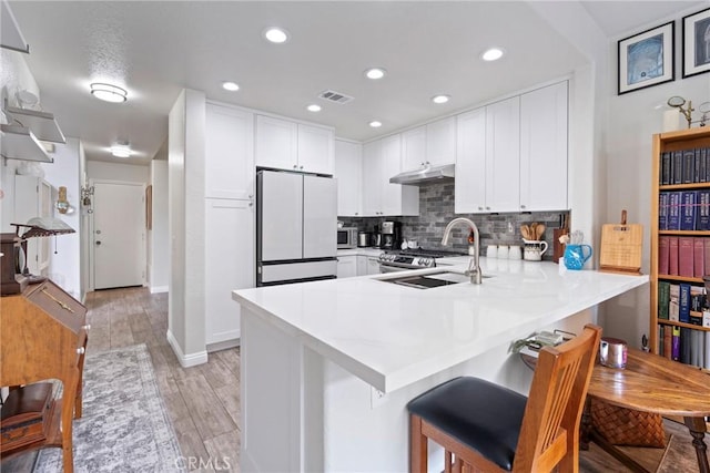 2141 Triador St Unit 103, Corona, CA 92879 - kitchen featuring freestanding refrigerator, a sink, a peninsula, light countertops, and backsplash