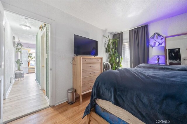 11100 S Normandie Ave, Los Angeles, CA 90044 - bedroom featuring a textured ceiling, wood finished floors, and baseboards