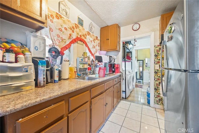 11100 S Normandie Ave, Los Angeles, CA 90044 - kitchen featuring freestanding refrigerator, a textured ceiling, light countertops, light tile patterned floors, and washer and dryer