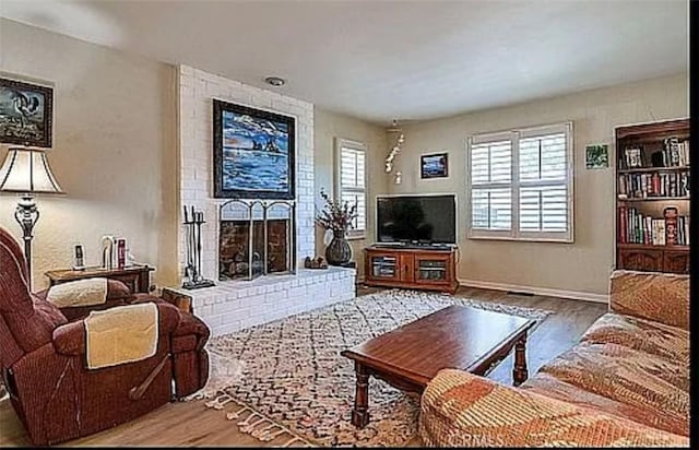 564 Northpark Blvd, San Bernardino, CA 92407 - living room featuring wood finished floors, a brick fireplace, and baseboards