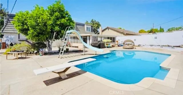 564 Northpark Blvd, San Bernardino, CA 92407 - view of pool with a diving board, a water slide, a patio area, and a fenced backyard