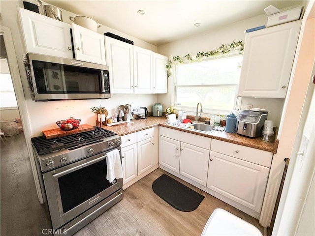 858 Bussey St, San Bernardino, CA 92405 - kitchen with appliances with stainless steel finishes, a sink, light wood-style floors, white cabinets, and light countertops