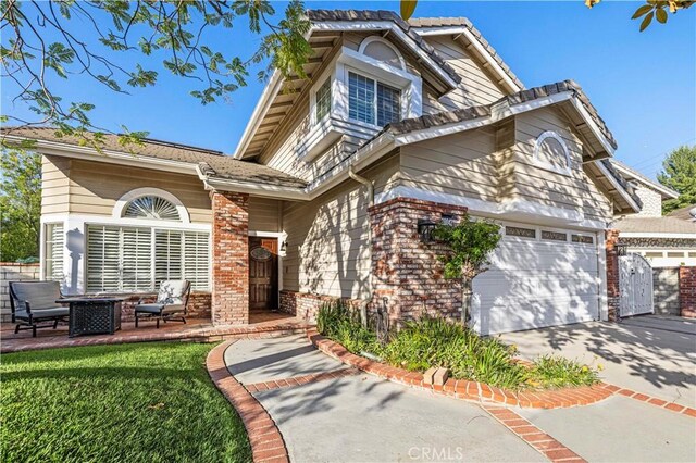 28642 Apricot Pl, Saugus, CA 91390 - view of front of house with an attached garage, brick siding, an outdoor fire pit, and driveway