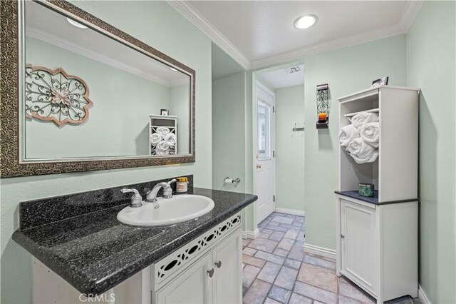 28642 Apricot Pl, Saugus, CA 91390 - bathroom featuring stone tile floors, vanity, baseboards, and crown molding
