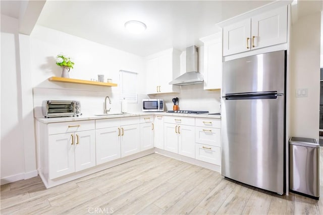 3720 S St Andrews Pl, Los Angeles, CA 90018 - kitchen with appliances with stainless steel finishes, wall chimney range hood, white cabinets, light wood-style floors, and light countertops