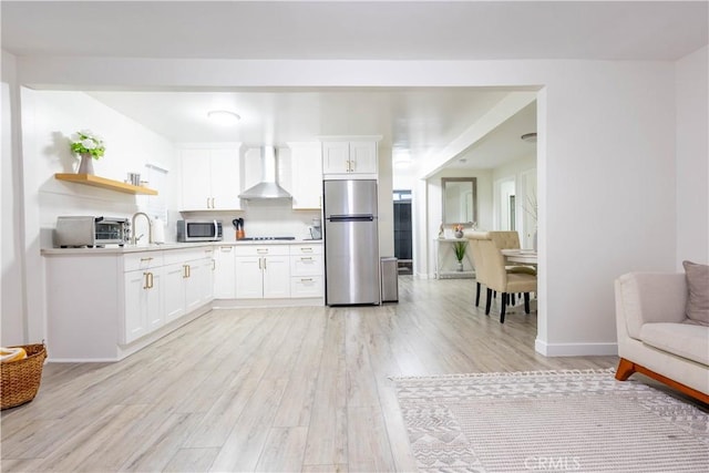3720 S St Andrews Pl, Los Angeles, CA 90018 - kitchen featuring stainless steel appliances, wall chimney range hood, open shelves, light wood finished floors, and white cabinetry