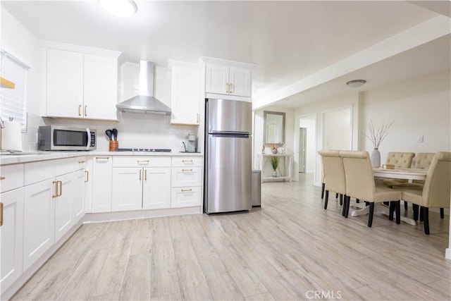 3720 S St Andrews Pl, Los Angeles, CA 90018 - kitchen featuring appliances with stainless steel finishes, wall chimney range hood, light countertops, tasteful backsplash, and white cabinets