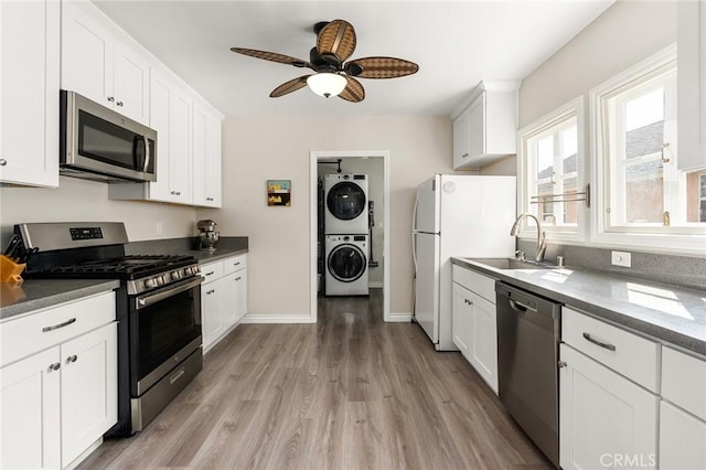 3648 4th Ave, Los Angeles, CA 90018 - kitchen featuring stainless steel appliances, stacked washer and clothes dryer, light wood-style flooring, ceiling fan, and white cabinetry