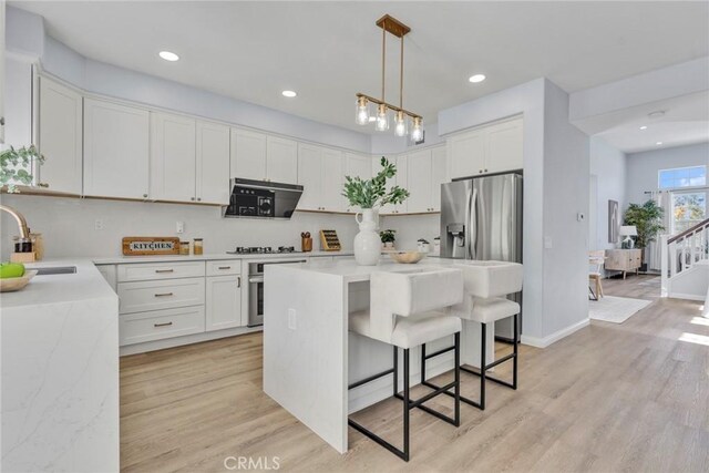 11376 Starlight Dr, Rancho Cucamonga, CA 91701 - kitchen with stainless steel appliances, light wood-style floors, a kitchen breakfast bar, a center island, and recessed lighting