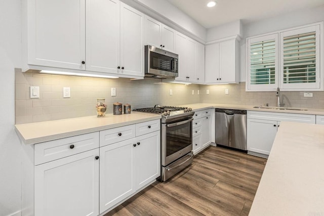 1003 Overton Ct, Tustin, CA 92780 - kitchen with appliances with stainless steel finishes, a sink, dark wood finished floors, white cabinets, and backsplash
