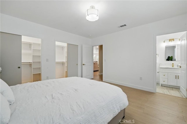 1217 W 77th St, Los Angeles, CA 90044 - bedroom with light wood-style floors, baseboards, a spacious closet, and connected bathroom