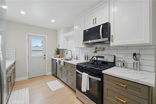 1217 W 77th St, Los Angeles, CA 90044 - kitchen featuring appliances with stainless steel finishes, light wood-style floors, decorative backsplash, a sink, and white cabinetry