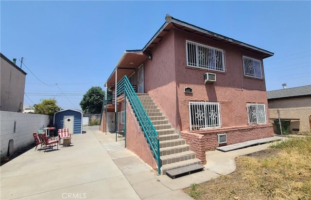 631 E 108th St, Los Angeles, CA 90059 - back of property featuring stairway, stucco siding, a patio area, and an AC wall unit