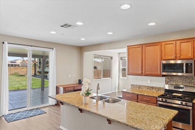 1472 Coyote Ln, Calimesa, CA 92320 - kitchen with appliances with stainless steel finishes, a sink, light wood-style floors, light stone counters, and recessed lighting
