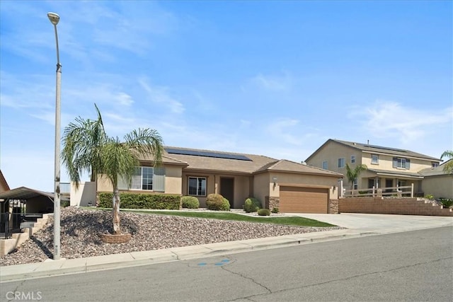 1472 Coyote Ln, Calimesa, CA 92320 - view of front facade with stucco siding, a garage, roof mounted solar panels, and driveway